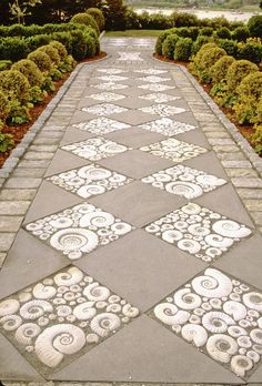 the walkway is made out of cement and has intricate designs on it, as well as plants