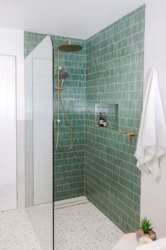 a green tiled bathroom with shower and sink