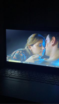 a man and woman kissing in front of a computer screen with the image on it