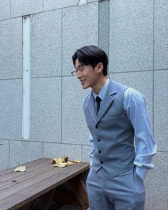 a man in a suit standing next to a wooden bench