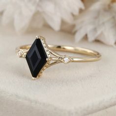 a black diamond ring sitting on top of a white flowered cloth next to it