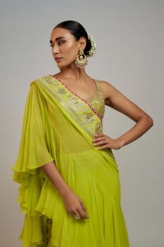 Editor's Note Channelize your feminine energy in this lime green sari. The sleeveless blouse, adorned with horizontal lines of silk and sequins, is paired with a chiffon ready-to-wear tiered sari featuring frills and volume. Green Sleeveless Pre-draped Saree For Festive Season, Festive Green Ruffled Saree, Green Georgette Saree With Ruffles, Green Ruffled Saree For Wedding, Green Georgette Blouse For Reception, Pista Green Georgette Blouse With Traditional Drape, Green Ruffled Pre-draped Saree For Reception, Designer Pista Green Georgette Blouse, Green Georgette Blouse With Traditional Drape