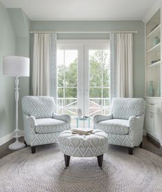 a living room with two chairs and a coffee table in front of a large window