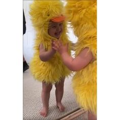 a baby in a chicken costume standing next to an adult