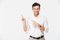 a man in a white shirt pointing to the side with his finger and smiling at the camera