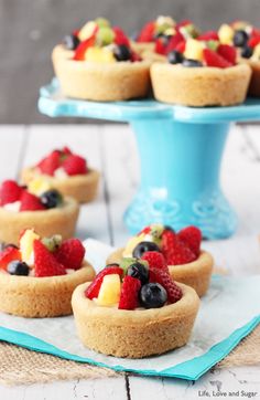 mini fruit tarts on a blue plate with a blue cake stand in the background