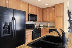 a black refrigerator freezer sitting inside of a kitchen next to a stove top oven