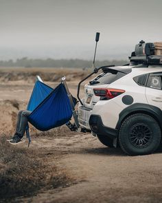 a white suv with a blue hammock strapped to it's roof