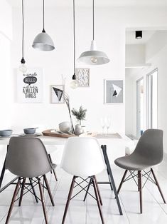 a dining room table with four chairs and three lights hanging from the ceiling above it