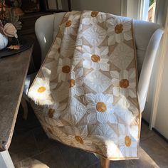 a white chair sitting next to a table with a blanket on it's back