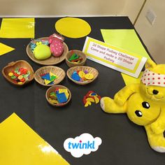 there is a yellow teddy bear sitting on the table next to other toys and decorations