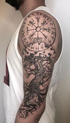 a man's arm with a tree and compass tattoo on it