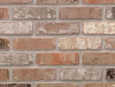 a red fire hydrant sitting on the side of a brick wall