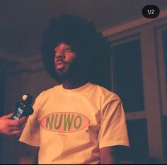 a man with an afro holding a bottle in his hand and wearing a nuwo t - shirt