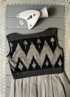 a black and white dress hanging on the wall next to an ironing board with scissors