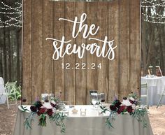 a sign that says the stewarts on top of a table with flowers and candles