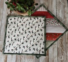 three quilted placemats sitting on top of a wooden table next to a potted plant