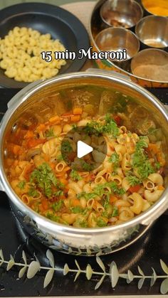 a pot filled with pasta and vegetables on top of a stove next to other cooking utensils