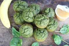 green muffins with spinach leaves next to a banana on a wooden table