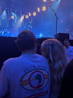 two people standing in front of a stage with lights