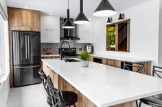 a kitchen with white counter tops and black chairs next to an island that has a potted plant on it