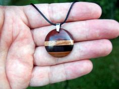 This domed circle necklace features a gorgeous combination of premium woods! Crafted from a hand-selected, artistic composition of domestic and exotic wood species. Carved into a an attractive modern dome shape. A hand rub finish is applied and then the pendant is buffed to a buttery smooth final finish that feels amazing to the touch. You can choose from a variety of necklace/cording options including: 18" or 22" stainless steel chain A variety of colors of satin cording with sliding knots that Round Wood Jewelry As A Gift, Round Wooden Jewelry For Gifts, Round Wooden Jewelry Gift, Handmade Round Wooden Jewelry, Handmade Round Natural Wood Jewelry, Brown Round Nature-inspired Necklaces, Nature-inspired Brown Round Necklaces, Brown Nature-inspired Round Necklaces, Round Brown Wooden Jewelry