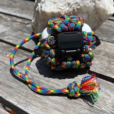 a multicolored paracording on a wooden table next to a white rock