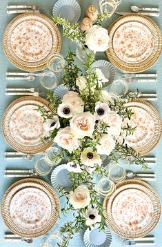 the table is set with plates, silverware and flowers