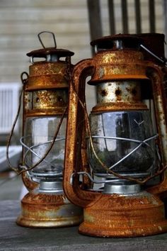 two old metal lanterns sitting on top of a wooden table