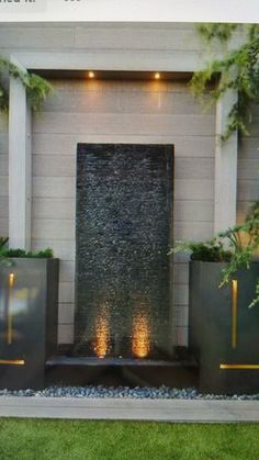 an outdoor fire place surrounded by two planters and some lights on the side of it