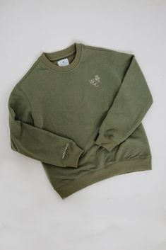 The WCC Crewneck features an embroidered logo design and a classic crewneck fit, making it a versatile and stylish addition to any wardrobe. Crafted from a blend of 84% cotton and 16% polyester, it offers both comfort and durability. Its olive green color adds a touch of style to level up any outfit. Classic Green Top With Embroidered Logo, Khaki Crew Neck Sweatshirt With Ribbed Cuffs, Green Sweatshirt With Embroidered Logo For Streetwear, Khaki Cotton Relaxed Fit Sweatshirt, Green Sweatshirt With Embroidered Logo For Fall, Khaki Crew Neck Sweatshirt For Fall, Olive Crew Neck Top For Winter, Sporty Khaki Crew Neck Sweatshirt, Everyday Crew Neck Sweatshirt With Embroidered Logo