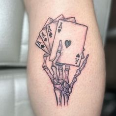 a tattoo on the leg of a person with four playing cards in their hands,