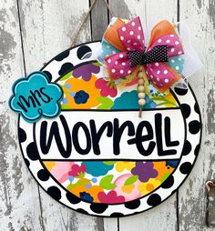 a colorful door hanger with the word worrel painted on it and a polka dot bow