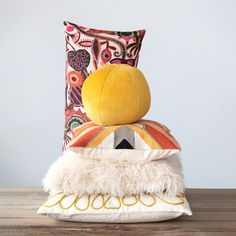 two pillows stacked on top of each other next to a pillow with an orange ball