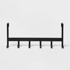 a black metal shelf with four hooks on it