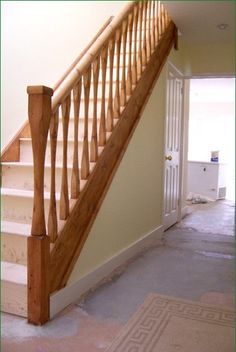 a wooden stair case next to a door in a room with beige walls and carpet on the floor