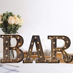 the letters bar are decorated with lights and flowers in front of a vase filled with roses