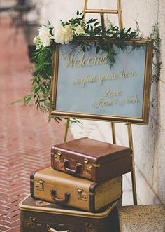 three suitcases stacked on top of each other in front of a welcome sign