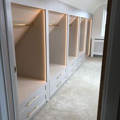 an empty walk - in closet with white cabinets and beige carpeted flooring is shown