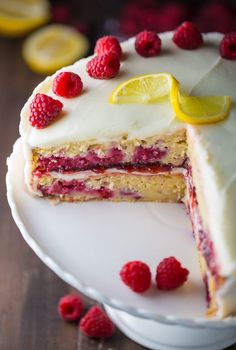 a cake with white frosting and raspberries on top is cut in half