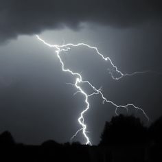 a lightning bolt is seen in the dark sky