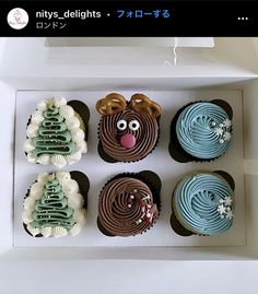 four decorated cupcakes in a white box