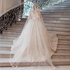 a woman in a wedding dress standing on some stairs with a veil over her head