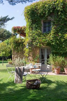 an outdoor table and chairs in front of a house with ivy growing on the walls