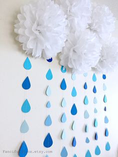 paper flowers and raindrops are hanging from the wall in front of a white background