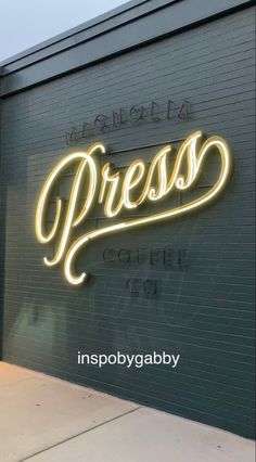 the neon sign on the side of a building reads press coffee