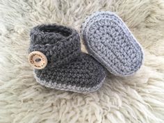 a pair of crocheted baby booties with a wooden button on the front