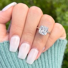 a woman's hand with a white manicure and a diamond ring on it