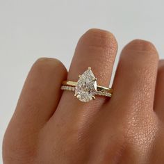 a woman's hand with a diamond ring on top of her finger and an engagement band