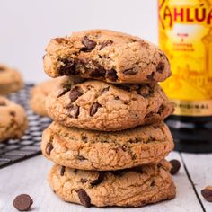 chocolate chip cookies stacked on top of each other with a bottle of beer in the background